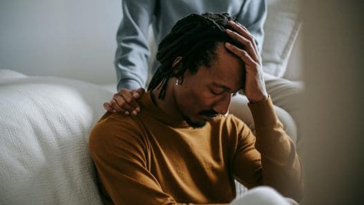 sorrowful black man touching head in dismay near supporting wife