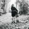 woman walking on pathway between green trees