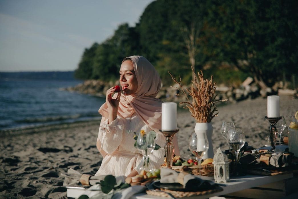 a woman wearing a hijab having a picnic at the beach
