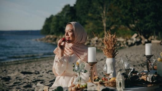 a woman wearing a hijab having a picnic at the beach
