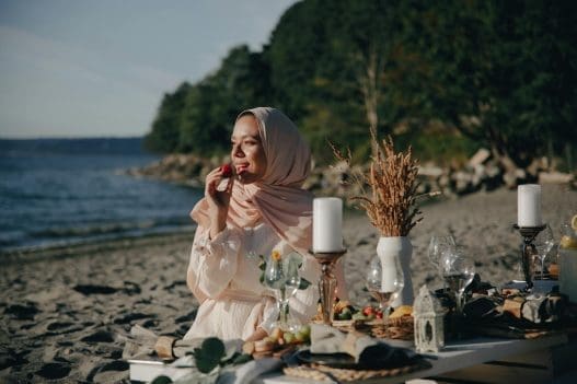 a woman wearing a hijab having a picnic at the beach