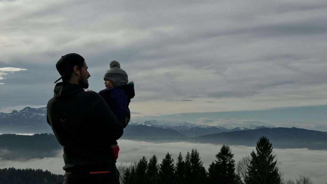 man holding a baby in a mountain landscape